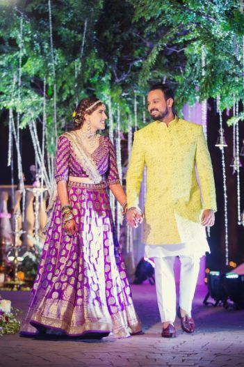 bride-groom-puja-ceremony-yellow-bandhgala-purple-lehenga-smiling-couple-the-bride-and-groom-don-contrasting-hues-and-look-like-a-million-bucks